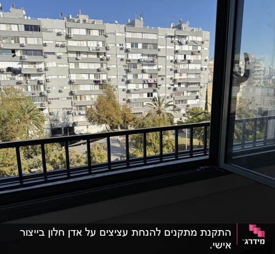 חלון פתוח עם מסגרת מתכת ונוף עירוני
